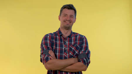 Happy young man bursting in laughter on yellow background. He is in checkered shirt. 4Kの写真素材