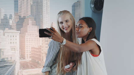 Behind the scenes on photo shoot: make-up artist applying makeup on model while she making selfie. Beautiful model has african ethnicity.の写真素材