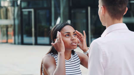Close-up of mixed-race girl quarreling with her boyfriend outdoors and then leaving him alone. Couple quarrel at a date.の写真素材