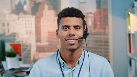 Close-up shot of mixed-race customer service operator talking to client in call center with skyscrapers in the background.の写真素材