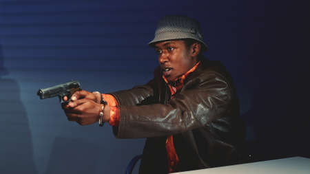 Close-up of black criminal grabbing the gun and threatening to harm cops. He trying to escape from interrogation room.の写真素材