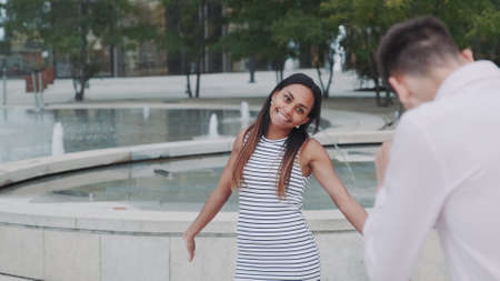Young man taking photo of his beautiful black girlfriend in city center. Fountains are in the background.の写真素材