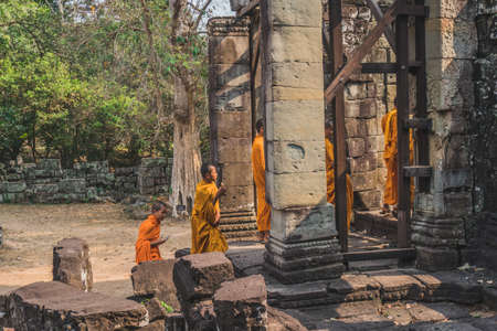 Young Buddhist Monks Walking In Temple In Saffron Robes and Looking Out Over Angkor Wat. Banteay Kdei Temple. Siem Reap, Cambodia - FEBRUARY 25, 2020のeditorial素材