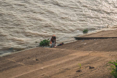 Woman washes clothes in the river. Phnom Penh, Cambodia - FEBRUARY 22, 2020のeditorial素材