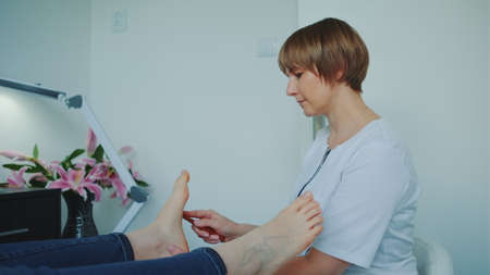Beautician making shiatsu foot massage using a wand. Relaxation at beauty spa salon.の写真素材