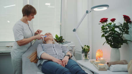 Professional cosmetologist making cavitation peeling on young womans face at beauty salon with modern equipment and pleasant atmosphere.の写真素材