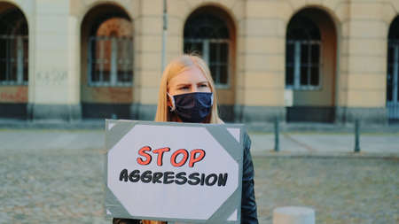 Protest walk: woman in protective mask protesting to stop aggression by holding steamer. She is upset by what is happening in the world.の写真素材