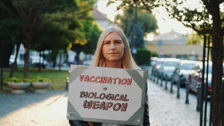 Young woman protesting against vaccination like biological weapon. She walking down the streetの写真素材