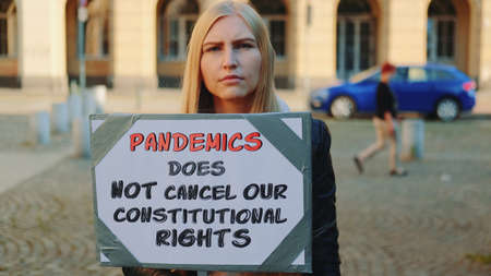 Protest walk declaring that pandemic does not cancel human constitutional rights. Woman with steamer walking on the street.の写真素材