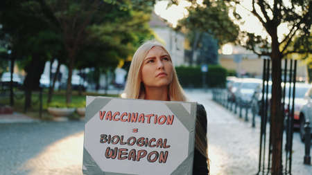 Young woman protesting against vaccination like biological weapon. She walking down the streetの写真素材