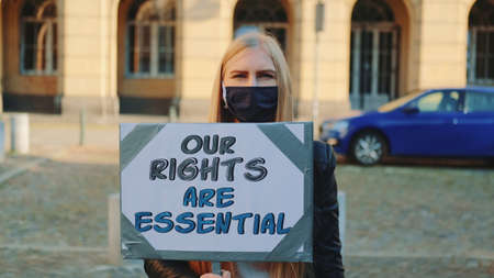 Protest walk: woman in protective mask urging to pay attention on human rights protection. She walking alone in the downtown.の写真素材