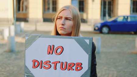 No disturb slogan on protest walk. Woman with steamer walking on the street.の写真素材