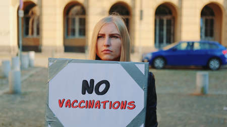 Young woman protesting against vaccination. She walking down the streetの写真素材