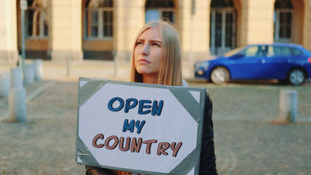 Young woman calling to open the country on protest walk. She holding steamer and walking on the street.の写真素材