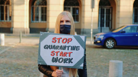 Young woman in protective mask calling to stop quarantine and start working. She worn protective mask and walking down the street.の写真素材