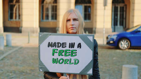 Made in a free world - slogan on protest actions in the city. Young blonde woman walking with steamer.の写真素材