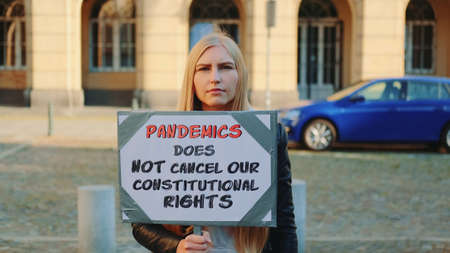 Protest walk declaring that pandemic does not cancel human constitutional rights. Woman with steamer walking on the street.の写真素材