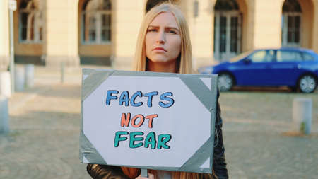 Facts not fear slogan on protest walk. Woman with steamer walking on the street.の写真素材