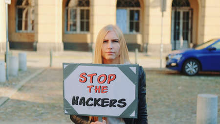 Concerned woman with protest banner calling to stop hackers by walking on the city streetの写真素材