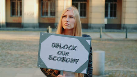 Young woman calling to unlock the economy by holding steamer. Protest walk in the city center.の写真素材