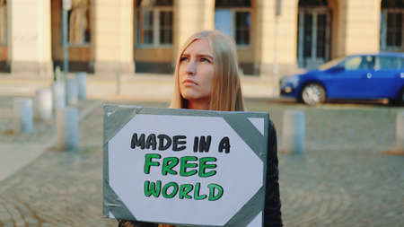Made in a free world - slogan on protest actions in the city. Young blonde woman walking with steamer.の写真素材