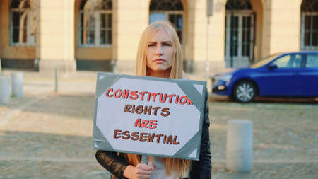 Protest walk: woman advocating for constitutional rights protection. She holding banner and going on the street.の写真素材