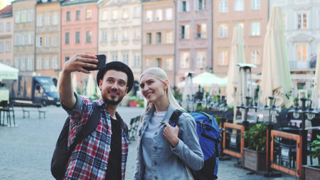 Happy young couple of tourists making selfie on smartphone in the city center. They have tourists...