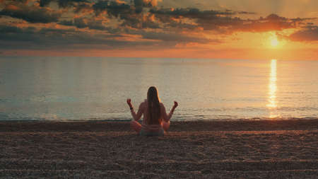 Full shot of woman meditating on the seashore. Back viewの写真素材