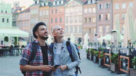 Young couple of tourists using smartphone and admiring beautiful surroundings. They going sightseeing early in the morning.の写真素材