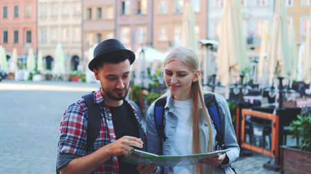 Medium shot of happy young couple of tourists checking map and then smiling to the camera.の写真素材