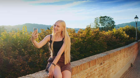 Woman making selfie on smartphone in front of beautiful nature landscape. Summer trip to another country.の写真素材