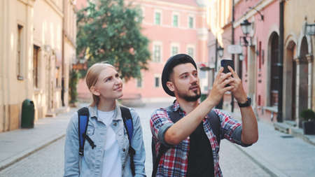 Young tourist couple walking on the street and making photos on smartphone. They admiring the beauty of surroundings.の写真素材
