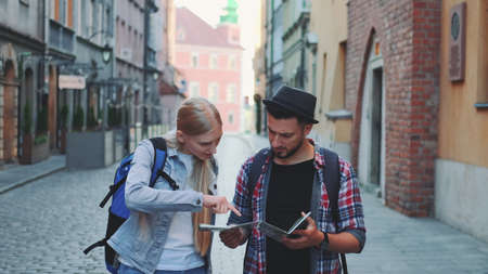 Two young tourists checking map while walking on main tourist street. They going sightseeing early in the morning.の写真素材