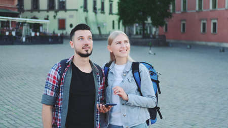 Happy tourists with smartphone finding beautiful place in the downtown of old european city. They are excited and smiled.の写真素材