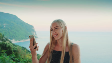 Woman providing video call with view on ocean. Vacations in warm countries.の写真素材
