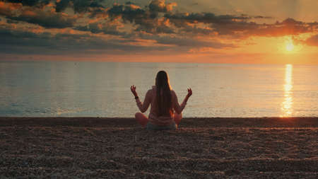 Woman meditating on the seashore. Back viewの写真素材