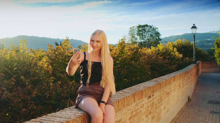 Pretty lady making selfie on smartphone in front of beautiful nature landscape. Summer trip to another country.の写真素材