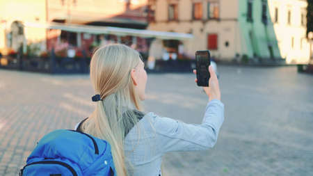 Back view of female tourist making video call on smartphone with her friend from other place. They exchanging impressions from travelings.の写真素材