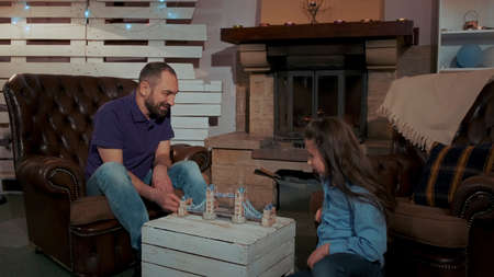 Happy dad and daughter spending their leisure time together at home near the fireplace in a pleasant atmosphereの写真素材
