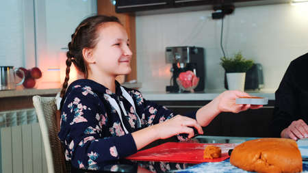 Smiling girl helping her mom to make gingerbread cookies. Family culinary and traditions concept.の写真素材