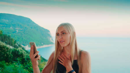Pretty woman providing video call with view on ocean. Vacations in warm countries.の写真素材