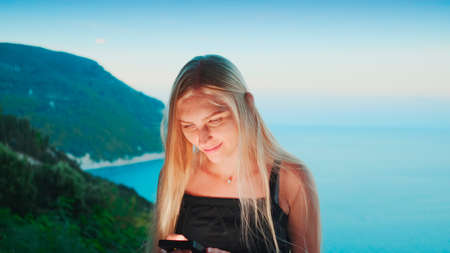 Woman using smartphone with ocean in the background. Vacations in warm countries.の写真素材