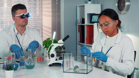 Black female research scientist making experiment with hamster in modern chemistry laboratory using pipette to drop some liquid to the container.の写真素材