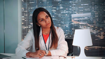 Close-up of african American psychologist attentively listening to patients story and writing notes in cosy office with skyscrapers in the backgroundの写真素材