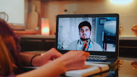 Close-up shot of Online medical consultation with doctor on computer from home. Woman writing his recommendations to the notebook.の写真素材