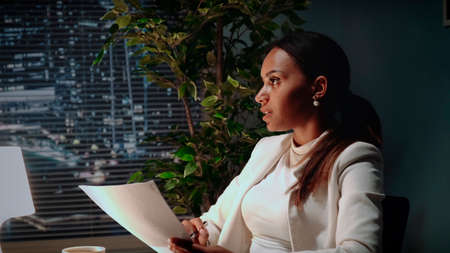 Beautiful african american business woman explaining the text of contract in office. There are skyscrapers in the background.の写真素材
