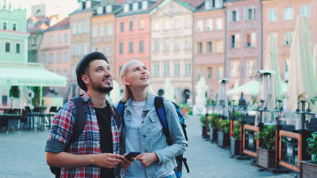 Young couple of tourists using smartphone and admiring beautiful surroundings. They going sightseeing early in the morning.の写真素材