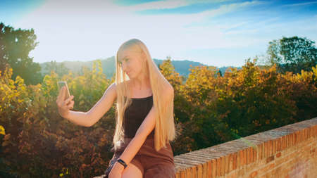 Woman making selfie on smartphone in front of beautiful nature landscape. Summer trip to another country.の写真素材