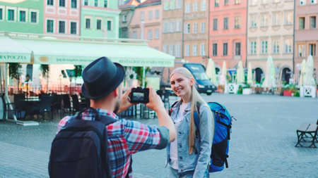 Young tourist couple making photos on the view of historical buildings. Woman posing. Man taking photos.の写真素材