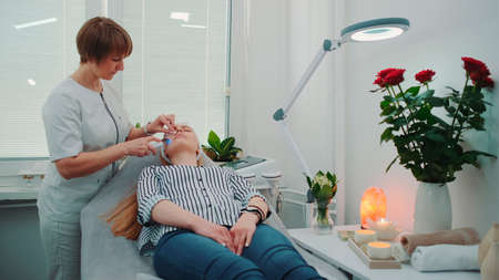 Professional cosmetologist making cavitation peeling on young womans face at beauty salon with modern equipment and pleasant atmosphere.の写真素材